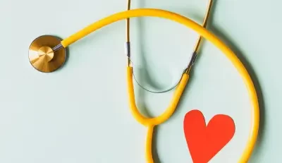 Yellow stethoscope and red heart on blue background representing health insurance care.