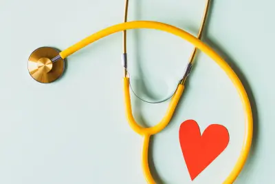 Yellow stethoscope and red heart on blue background representing health insurance care.