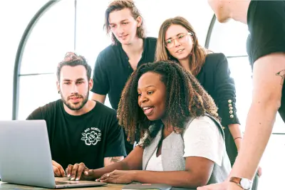 Federal employees collaborating on retirement estimates around a laptop in a modern office setting.