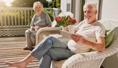 Retired couple relaxing on a porch, enjoying federal retirement benefits.