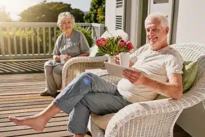 Retired couple relaxing on a porch, enjoying federal retirement benefits.