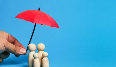 Wooden family figures under a red umbrella symbolizing protection and Federal employee insurance.