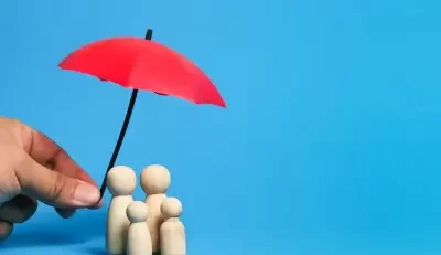 Wooden family figures under a red umbrella symbolizing protection and Federal employee insurance.