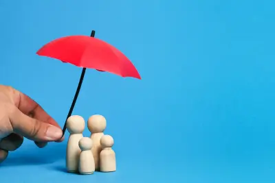 Wooden family figures under a red umbrella symbolizing protection and Federal employee insurance.