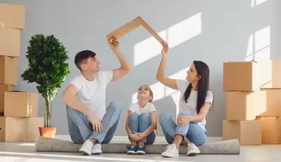 A happy family sitting together with a paper roof symbolizing protection and security.