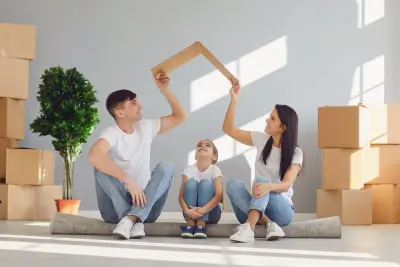 A happy family sitting together with a paper roof symbolizing protection and security.