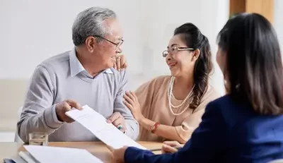 Smiling couple discussing FERS retirement plan with a professional advisor at a desk.
