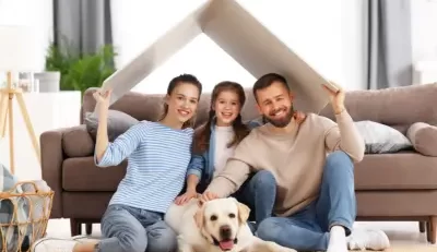 Family sitting together with a dog under a roof-like cover, symbolizing protection with supplemental life insurance.